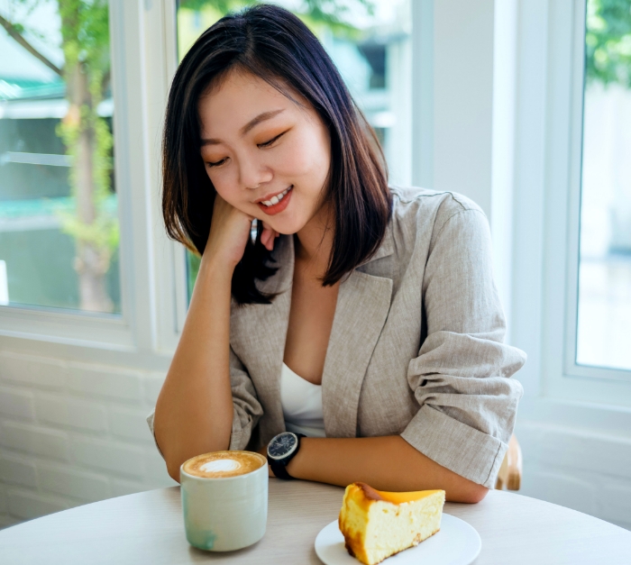 A Lactose Intolerant woman with cake and dairy drink on the table